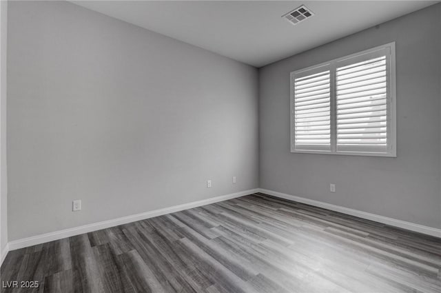 unfurnished room with baseboards, visible vents, and wood finished floors