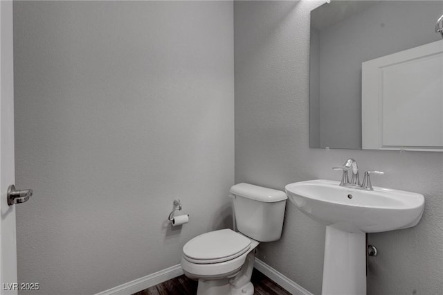 bathroom featuring toilet, wood finished floors, and baseboards