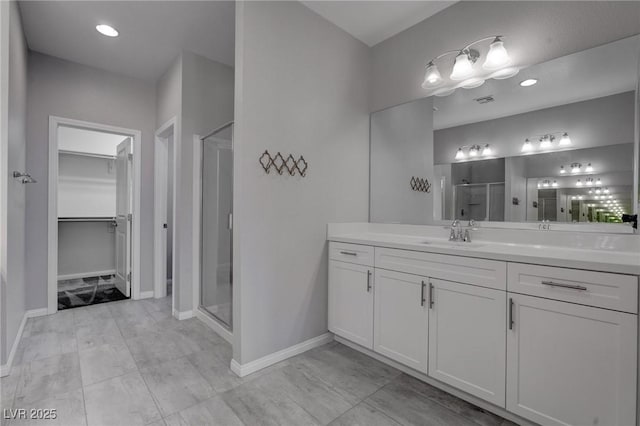 full bath with a stall shower, a spacious closet, vanity, and baseboards