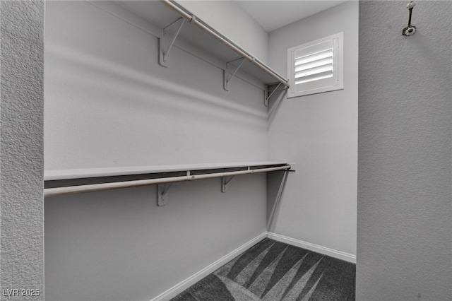 walk in closet featuring dark carpet