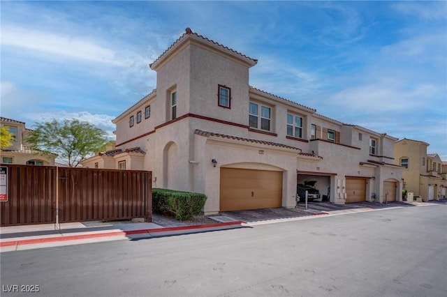view of front of home with a tile roof, fence, a garage, and stucco siding