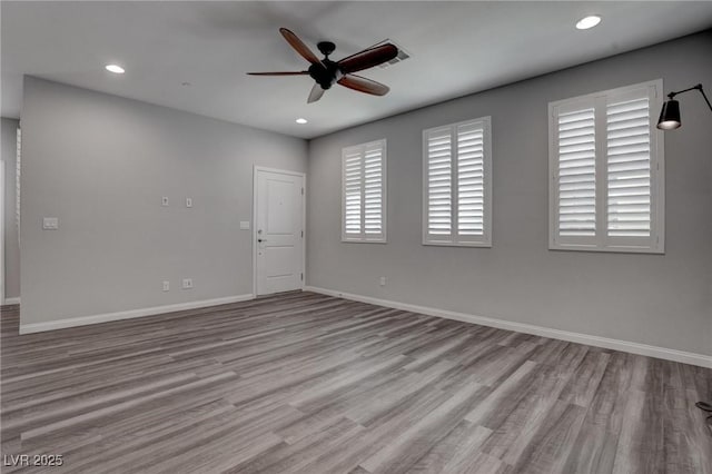 empty room featuring wood finished floors, baseboards, and ceiling fan