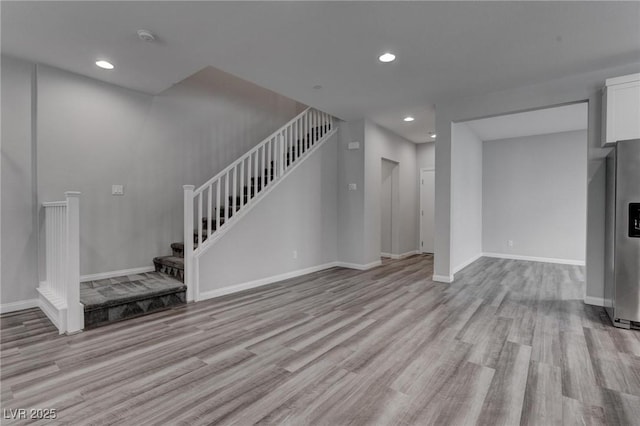 unfurnished living room with baseboards, stairs, recessed lighting, and light wood-type flooring