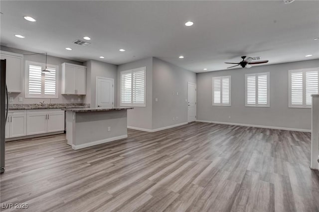 kitchen with white cabinetry, ceiling fan, visible vents, and a wealth of natural light