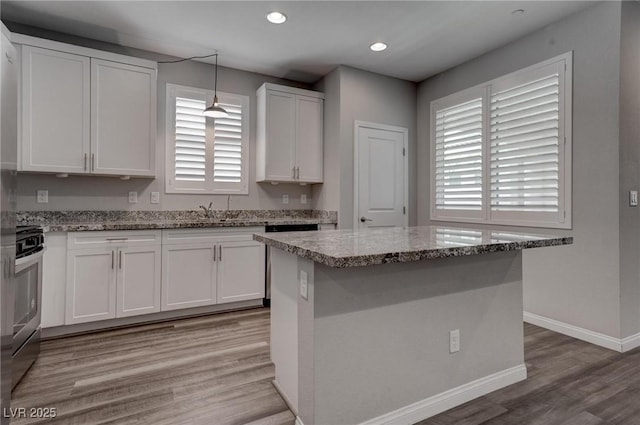 kitchen featuring a sink, light wood-style flooring, light stone countertops, and white cabinets