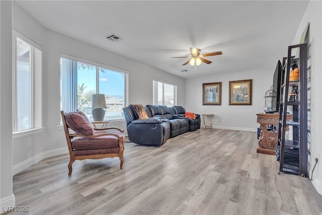 living room with light wood-style floors, baseboards, visible vents, and a ceiling fan