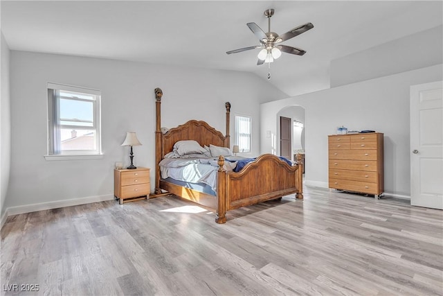 bedroom with arched walkways, light wood finished floors, multiple windows, and baseboards