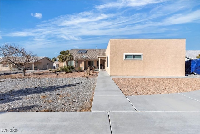 pueblo revival-style home featuring solar panels and stucco siding