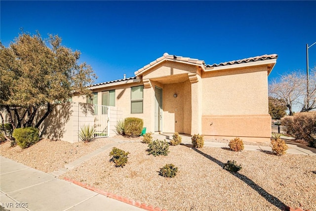 view of front facade featuring a tiled roof, fence, and stucco siding