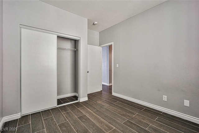 unfurnished bedroom featuring wood tiled floor, baseboards, and a closet