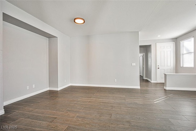 spare room with a textured ceiling, baseboards, and wood finished floors