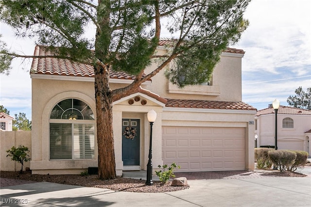 mediterranean / spanish-style home with a tile roof, driveway, and stucco siding