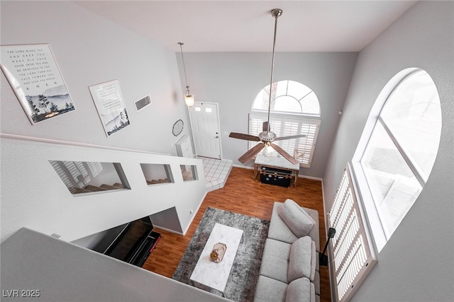 living area with a ceiling fan, vaulted ceiling, baseboards, and wood finished floors