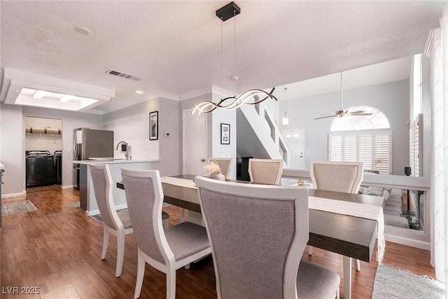 dining area with baseboards, visible vents, ceiling fan, wood finished floors, and washing machine and dryer