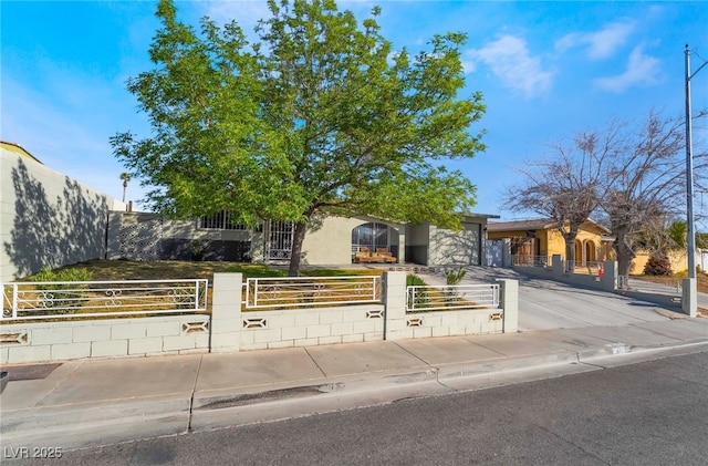 obstructed view of property featuring a fenced front yard, concrete driveway, an attached garage, and a gate