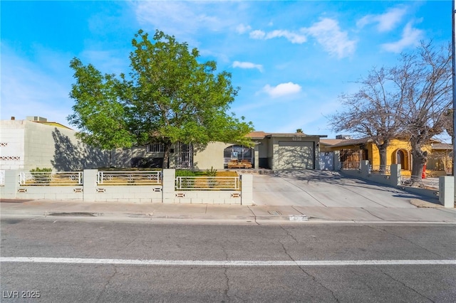 obstructed view of property featuring a garage, driveway, and a fenced front yard