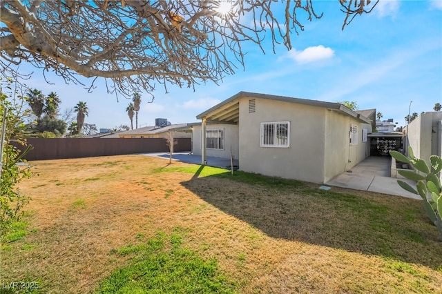 rear view of house with a patio area, a fenced backyard, a yard, and stucco siding