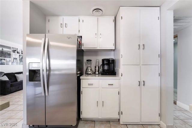 kitchen with light tile patterned floors, visible vents, light countertops, white cabinetry, and stainless steel refrigerator with ice dispenser