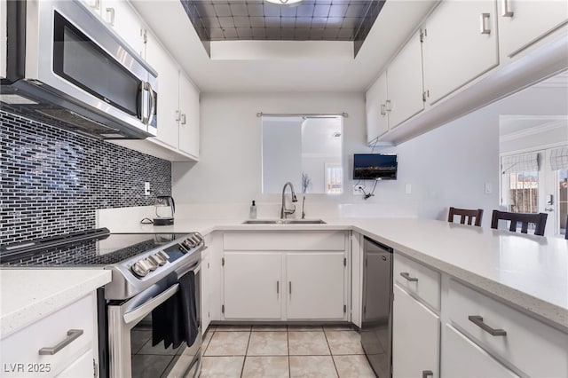 kitchen featuring stainless steel appliances, white cabinets, light countertops, and a sink