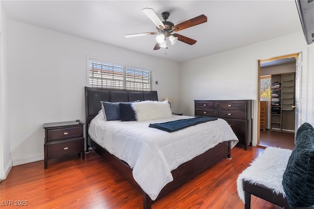 bedroom featuring baseboards, dark wood finished floors, and a ceiling fan