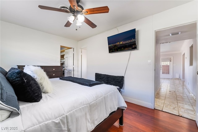 bedroom with a ceiling fan, visible vents, dark wood finished floors, and baseboards