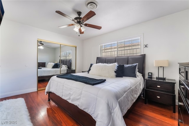 bedroom featuring dark wood-style flooring, a closet, visible vents, a ceiling fan, and baseboards