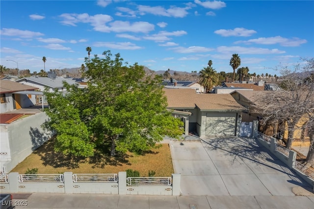 view of property hidden behind natural elements with a fenced front yard, a garage, driveway, a residential view, and a gate