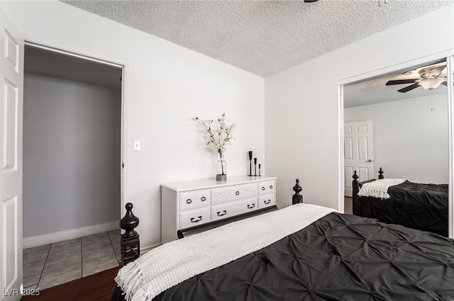 bedroom featuring dark tile patterned flooring, a textured ceiling, and baseboards