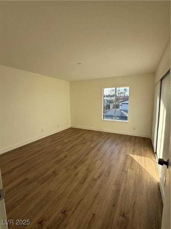 unfurnished bedroom with dark wood-type flooring and baseboards