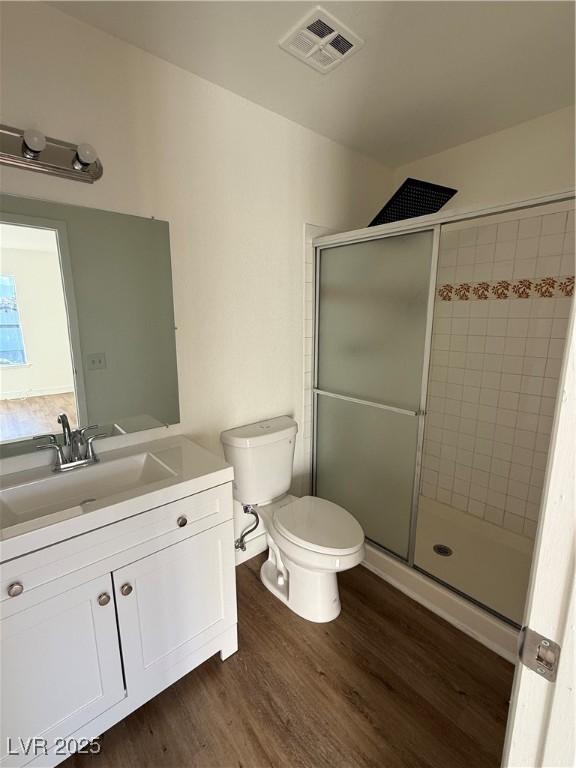 bathroom featuring vanity, a stall shower, wood finished floors, and visible vents