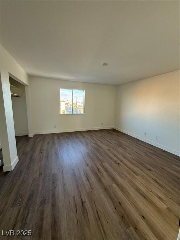 unfurnished room with dark wood-style flooring and baseboards