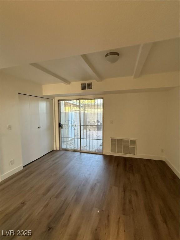 unfurnished room featuring baseboards, visible vents, and dark wood finished floors