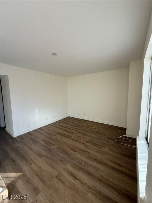 unfurnished room featuring vaulted ceiling, dark wood-type flooring, and baseboards