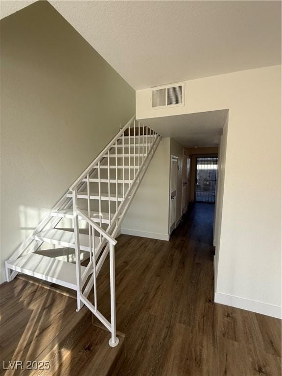 staircase featuring baseboards, visible vents, and wood finished floors