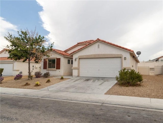 mediterranean / spanish house with stucco siding, concrete driveway, fence, a garage, and a tiled roof