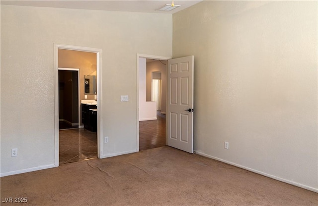 unfurnished bedroom featuring carpet floors, visible vents, ensuite bath, and baseboards