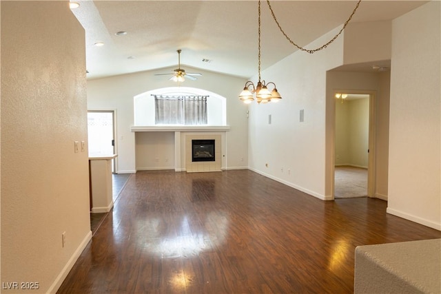 unfurnished living room with baseboards, a ceiling fan, a tiled fireplace, lofted ceiling, and dark wood-type flooring