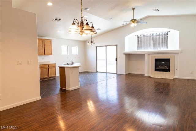 unfurnished living room featuring visible vents, dark wood-type flooring, vaulted ceiling, a sink, and a tile fireplace