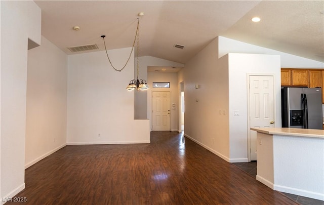 kitchen featuring brown cabinets, stainless steel refrigerator with ice dispenser, lofted ceiling, visible vents, and light countertops