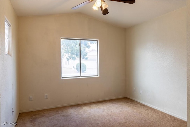 empty room featuring lofted ceiling, light carpet, ceiling fan, and baseboards