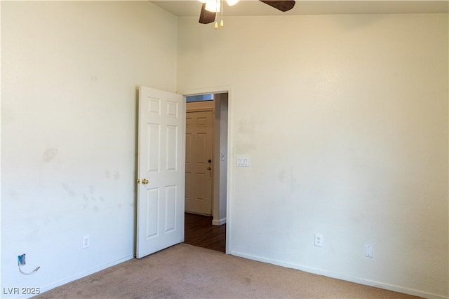 empty room with light carpet, a ceiling fan, and baseboards