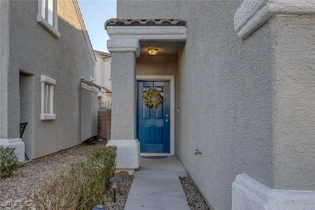 property entrance with fence, a tile roof, and stucco siding