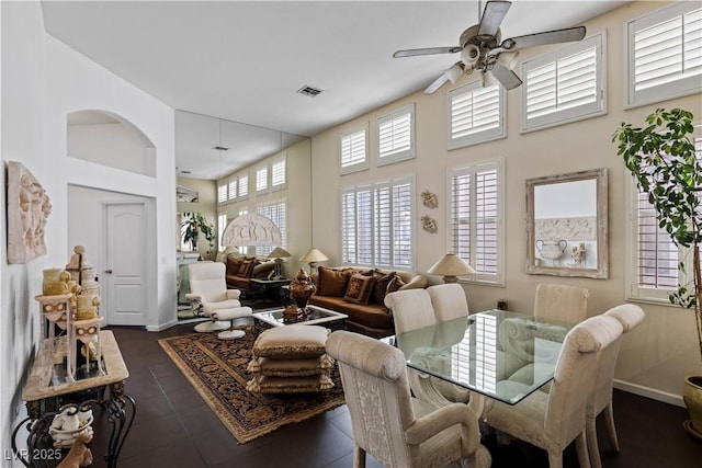 dining space with a ceiling fan, visible vents, a towering ceiling, and baseboards