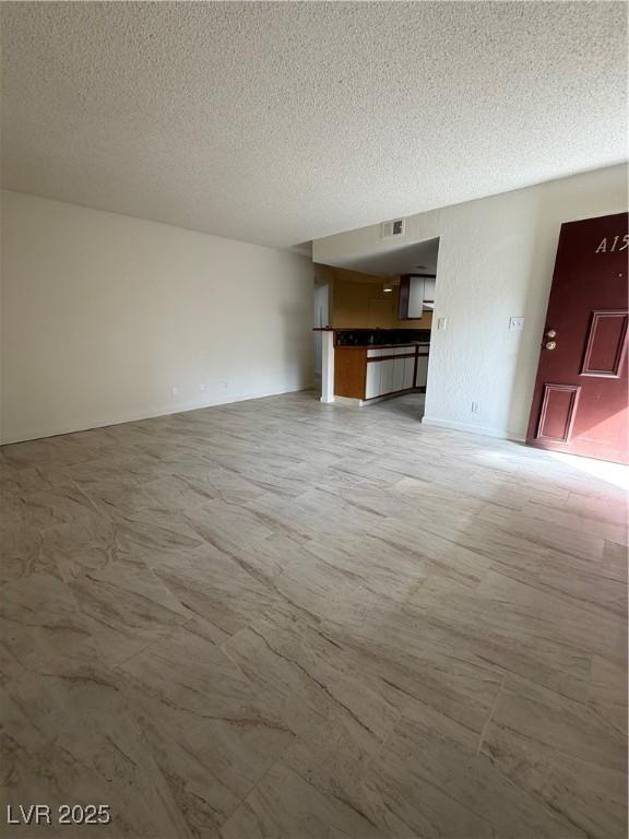 unfurnished living room with a textured ceiling and visible vents