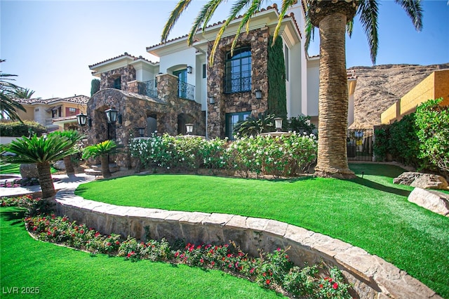 view of front of house with stone siding, a tiled roof, a front lawn, and stucco siding