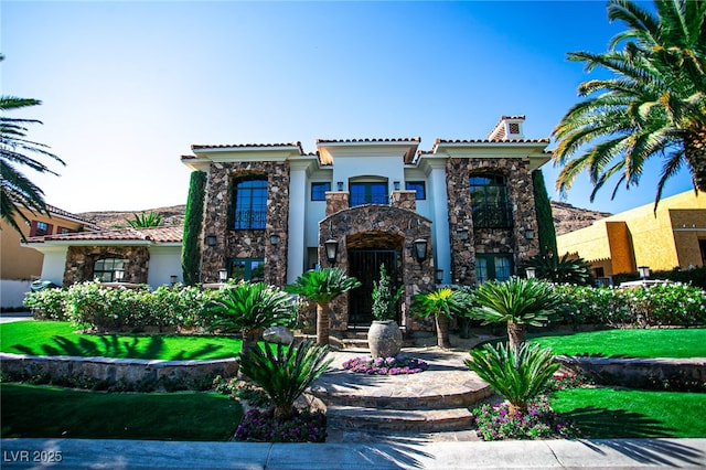 mediterranean / spanish house featuring a balcony, a tile roof, stone siding, stucco siding, and a chimney