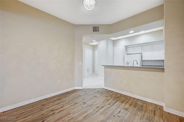 empty room featuring light wood-style floors, recessed lighting, visible vents, and baseboards