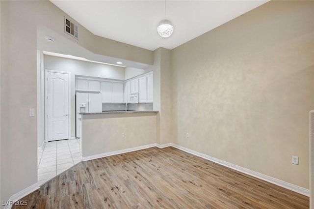 interior space with baseboards, visible vents, and light wood-style floors