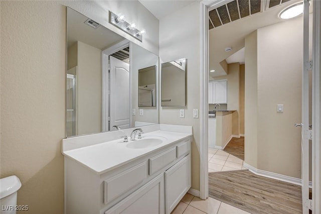 bathroom featuring visible vents, toilet, vanity, baseboards, and tile patterned floors