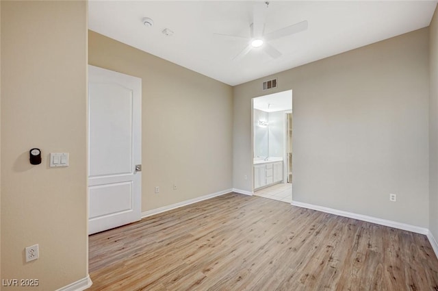 empty room featuring light wood-style floors, ceiling fan, visible vents, and baseboards